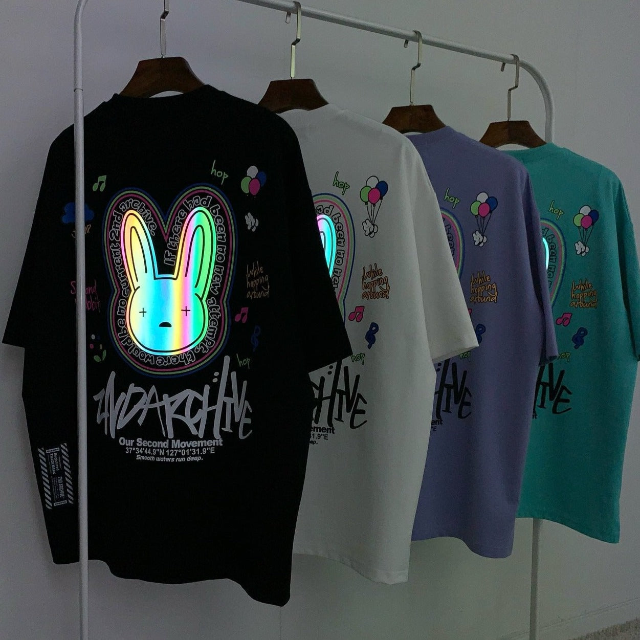 Four t shirts with cool reflective graphics hanging on a rack.