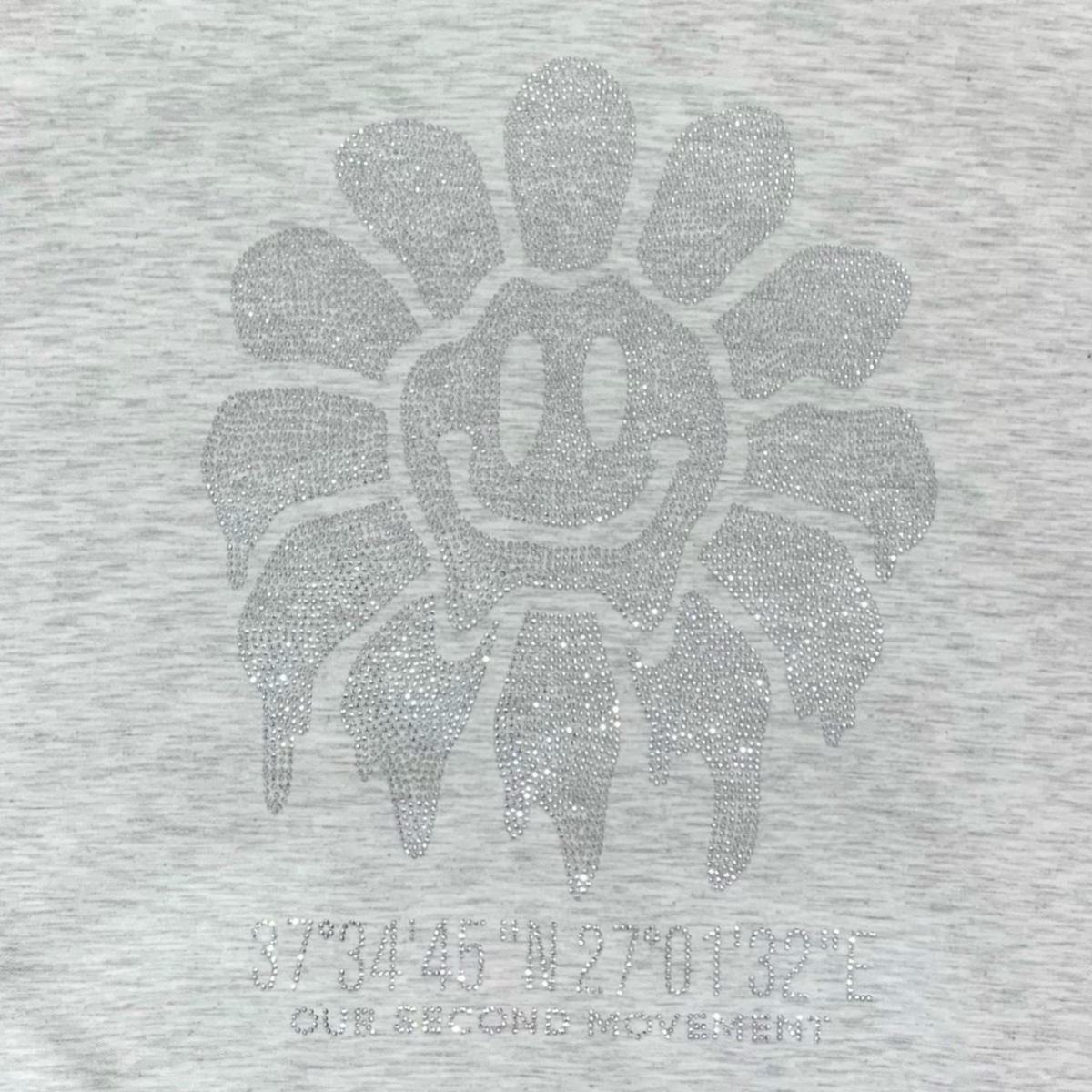 ライトグレーのスマイルフラワースタッズが光を受けるアップ写真