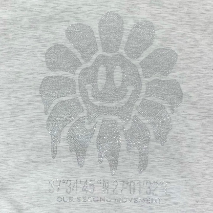 ライトグレーのスマイルフラワースタッズが光を受けるアップ写真