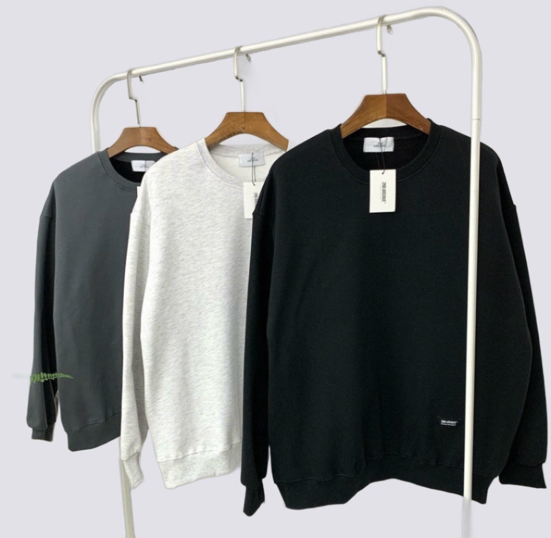 Three sweaters hanging on a rack made in Korea. 