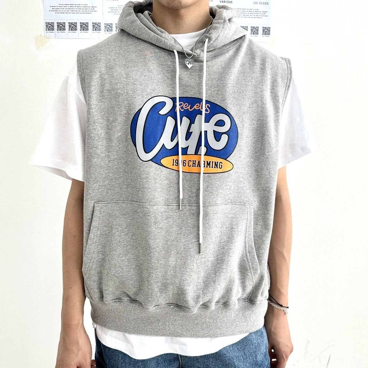 Korean model wearing a gray sleeveless hoodie with English writing on the chest. 