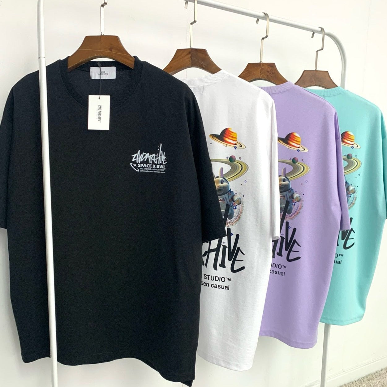 black, white, purple and light blue Korean fashion t-shirts with graphics hanging on a rack.  