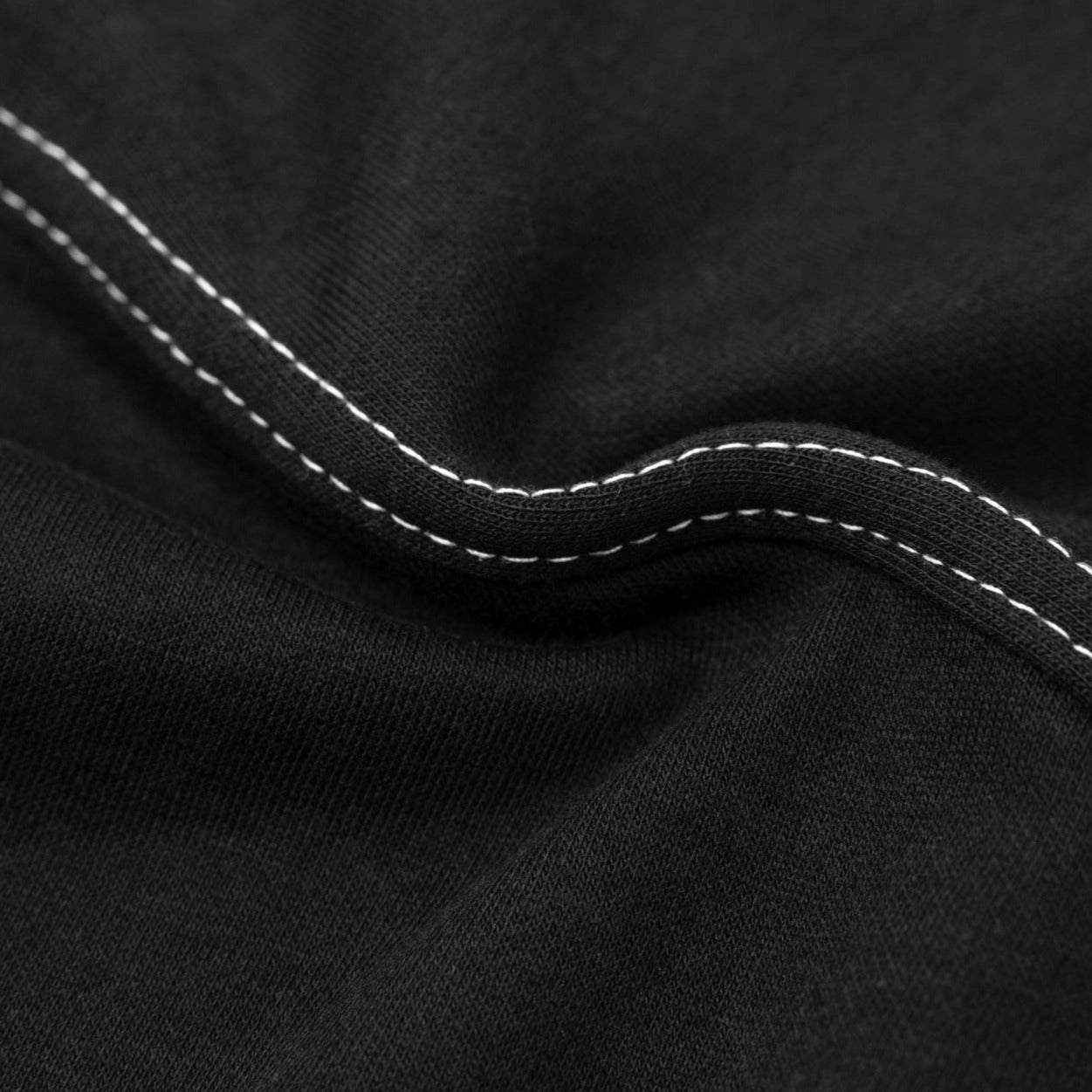 Close up of double stitching on black unisex long sleeve shirt made in Korea. 