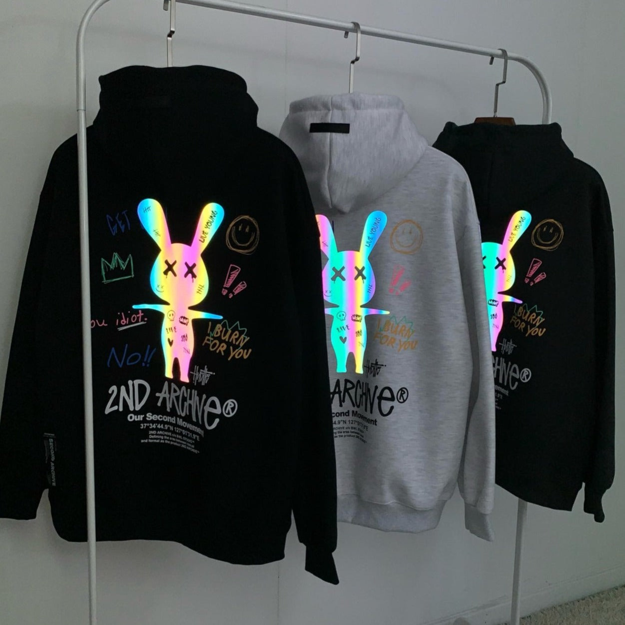 Glow in the dark bunny graphics on hoodie sweaters hanging on rack. 