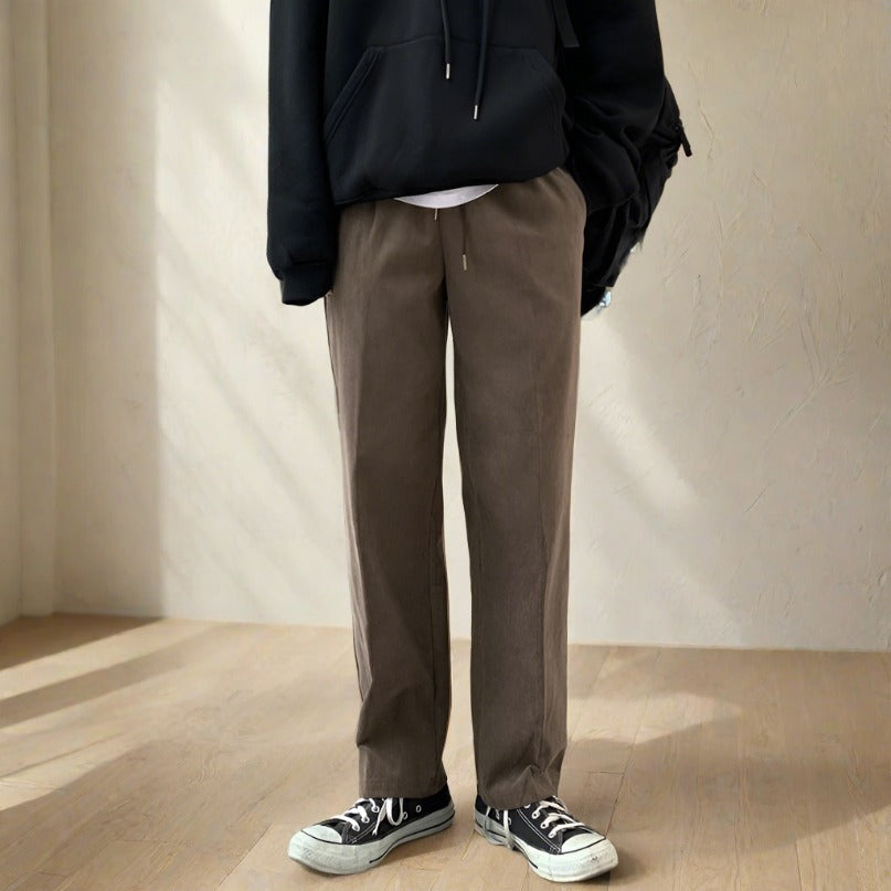 Korean model wearing brown slacks standing in a room. 