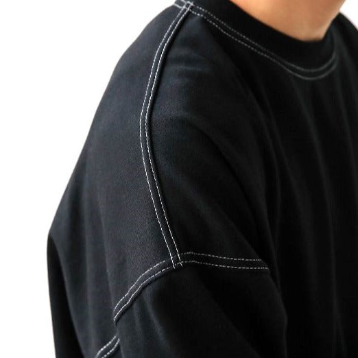 Close up of detailed double-stitched shoulder of black long-sleeve shirt. 