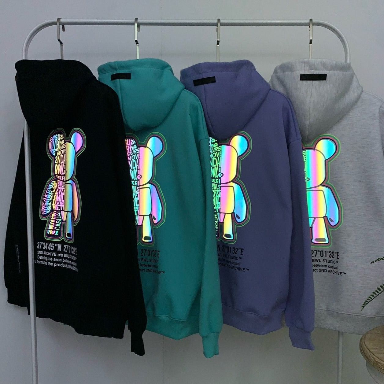 Four color options of Korean street fashion hoodie sweaters hanging on rack. 