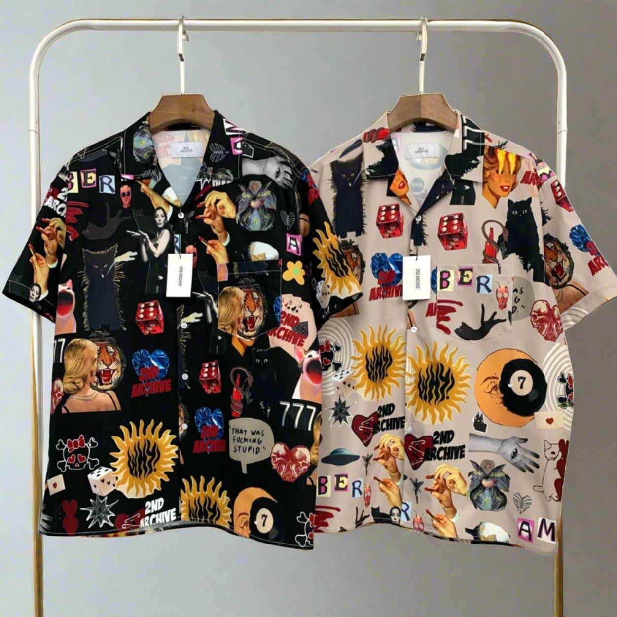 Two front facing pop art short sleeve shirts hanging on a rack. 