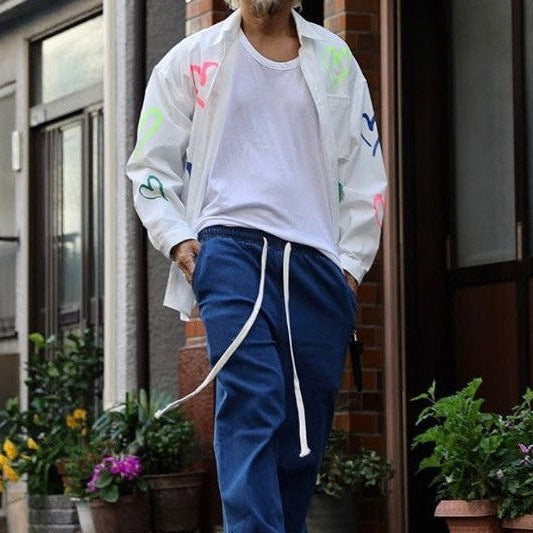 Model wearing unbuttoned street fashion shirt standing on the corner. 