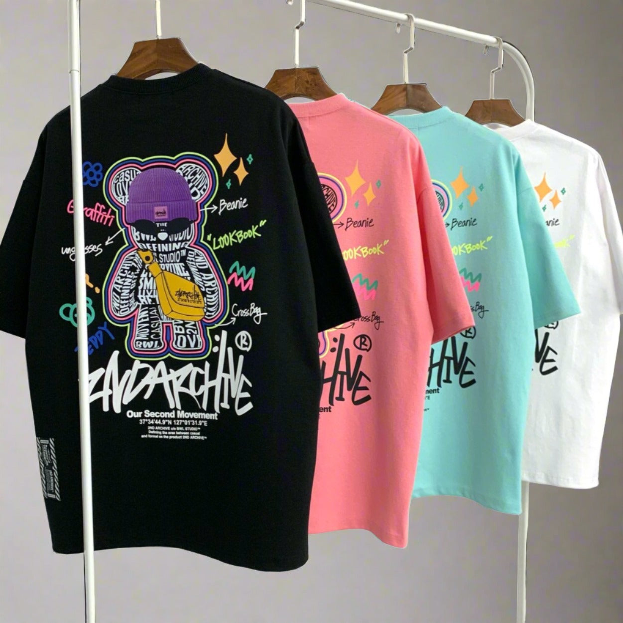 Black, pink, mint and white street fashion graphic t shirts hanging on a rack. 